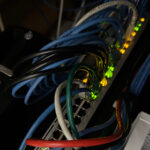 A UniFi USW-PoE-48 Ethernet switch vertically oriented with cables plugged-in, and showing status LEDs